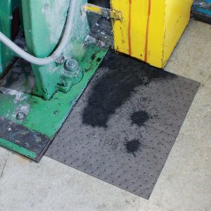 Industrial absorbent mat soaking up oil from leaking machinery